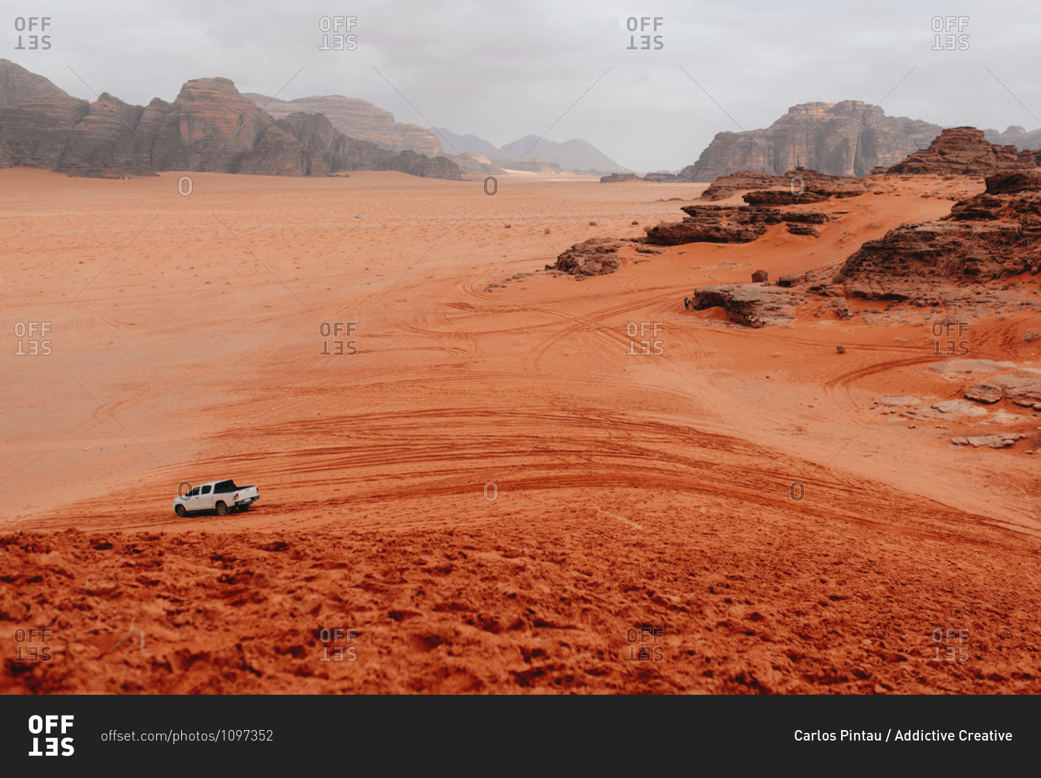 Scenic view of automobile riding in sandstone valley in Wadi Rum on cloudy day