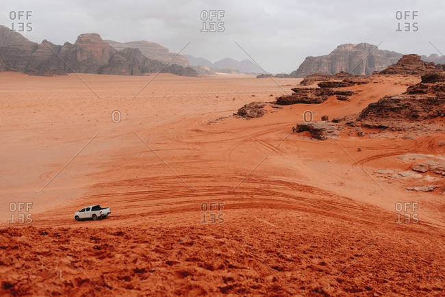 Scenic view of automobile riding in sandstone valley in Wadi Rum on cloudy day