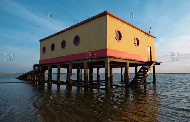 Lifeguard house located on wet sandy Fuseta Beach on background of sea and sunset sky in Algarve