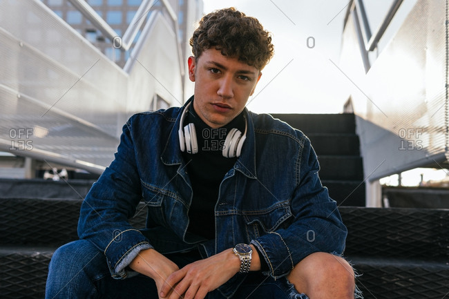 Young male with curly hair wearing denim clothes with wireless