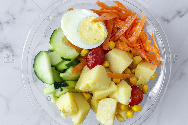 From above of various delicious vegetables and boiled egg placed in plastic container for takeaway food