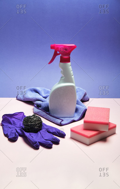 Top view of latex gloves and spray detergent arranged on pink and blue background with sponges and rag for cleaning concept