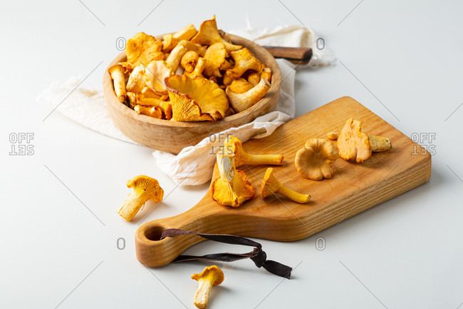 Mushrooms chanterelles in a wooden bowl and on cutting board
