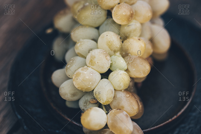 Close up of a bunch of white grapes on a black plate