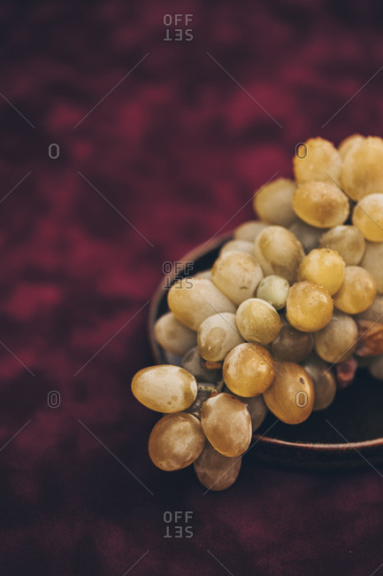 Close up of plate filled with white grapes on burgundy background