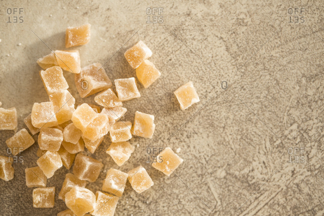 Candied ginger pieces in a pile on stone background
