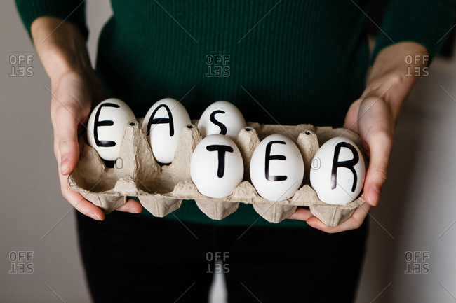 Woman holding chicken eggs with Easter written on them in a package made of recycled paper