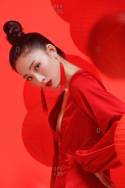 Profile view of a young female Chinese model wearing red against a backdrop of red lanterns