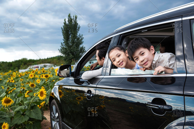Children looking out back window of a black vehicle while on a family outing to the countryside