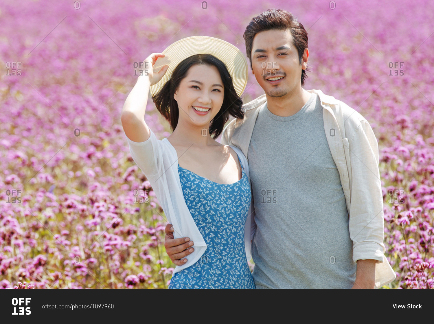 Happy young couple standing together in a field of purple flowers