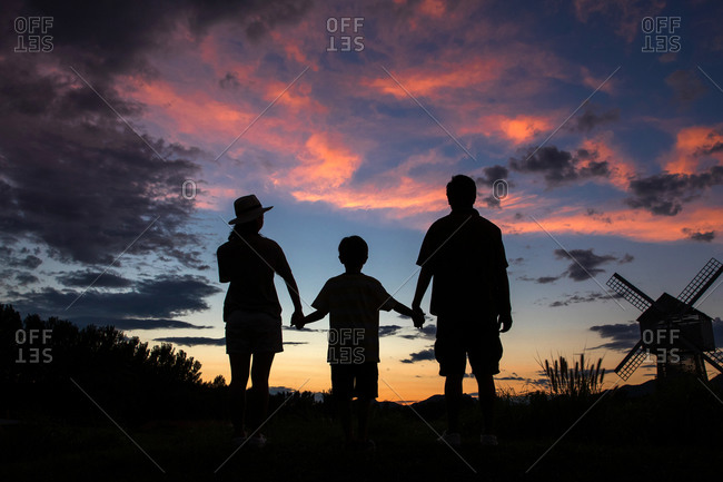 Silhouette Of Parents And Child Holding Hands In Front Of The Sunset Sky Stock Photo Offset