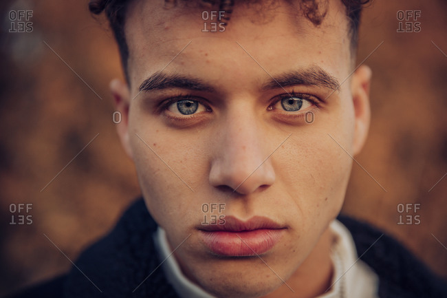 Young man with blue eyes in autumn forest