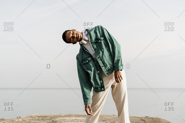 Young man on pier against sky and sea