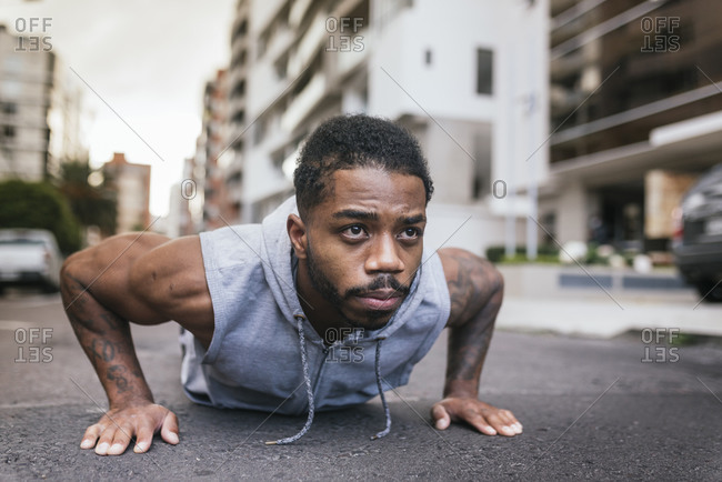 Afro sportsman doing push-ups on street