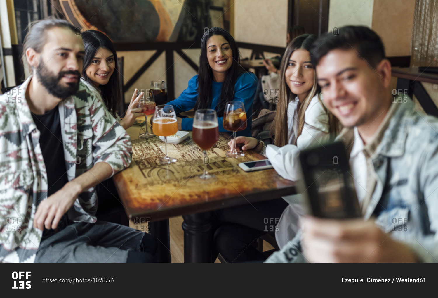 Happy friends taking selfie through smart phone in bar