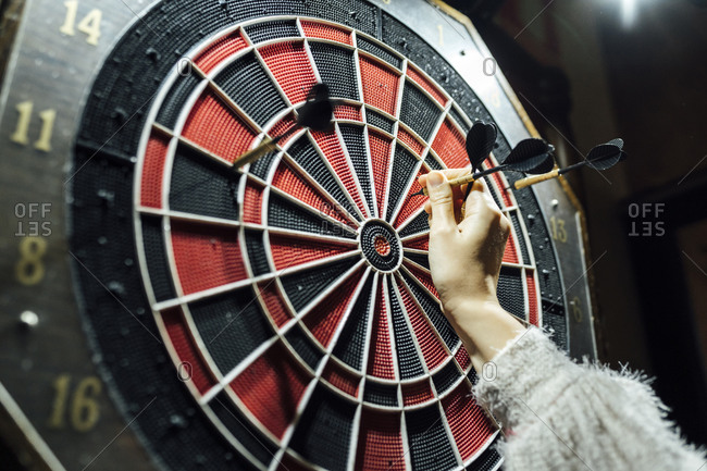 Woman's hand collecting darts from board