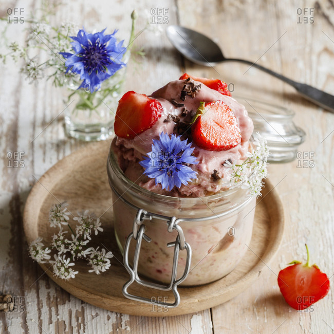 Jar of mashed bananas with espresso- strawberries and cornflowers