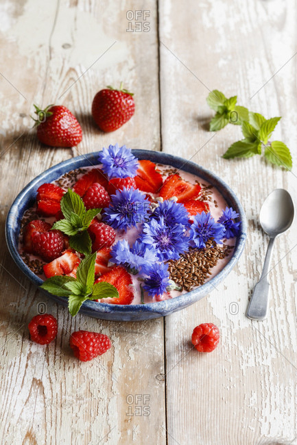 Plate of yogurt with raspberries- strawberries- cornflowers and mint