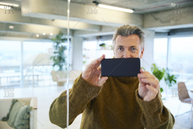 Man taking photo through mobile phone at home