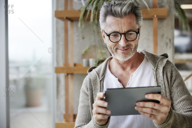 Mature man smiling while using digital tablet