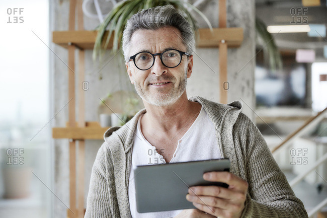 Man wearing eyeglasses using digital tablet