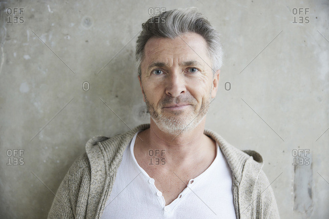 Man with blue eyes standing against wall