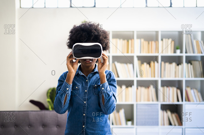 Woman using virtual reality headset while standing at home