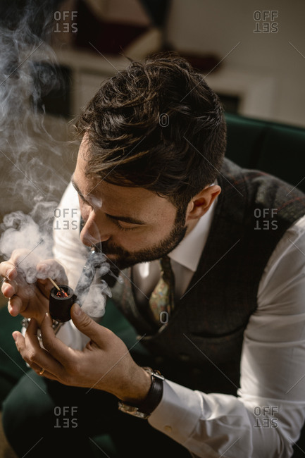 Bearded man smoking pipe alone