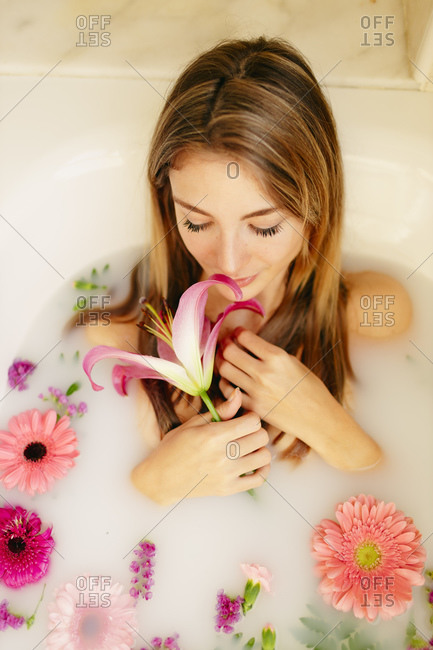 Woman smelling flower while having bath at spa