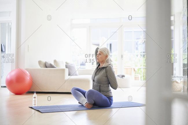 Senior woman exercising with hands behind back in living room