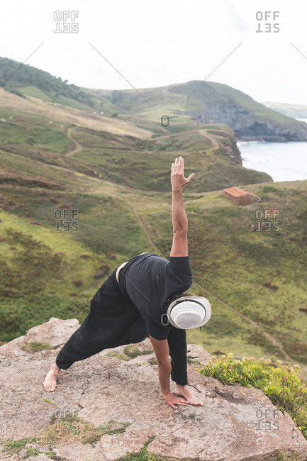 Young man doing yoga pose on rock mountain at Santander- Spain
