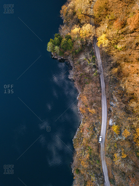 Aerial view of country road stretching along shore of Lake Ritsa in autumn