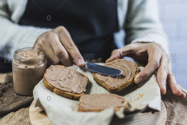 Hands of man spreading wholegrain bread slices with homemade cocoa cream
