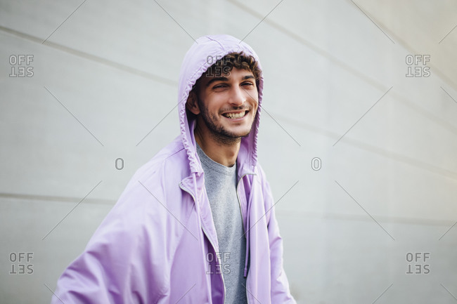 Smiling man in violet jacket against gray wall