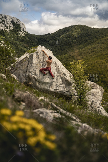 Boulderer climbing rock in mountain landscape