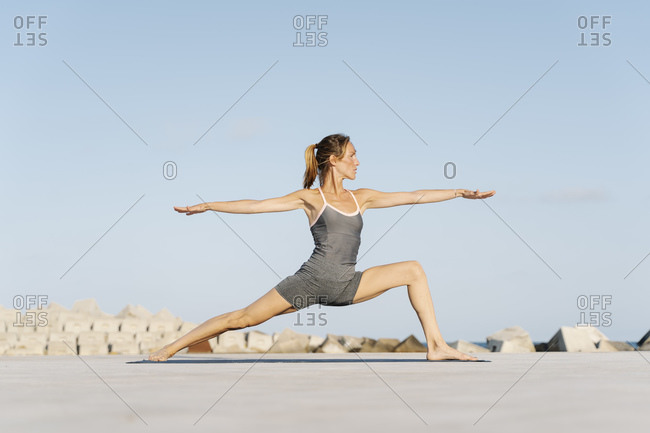 Female sportsperson doing warrior position on exercise mat