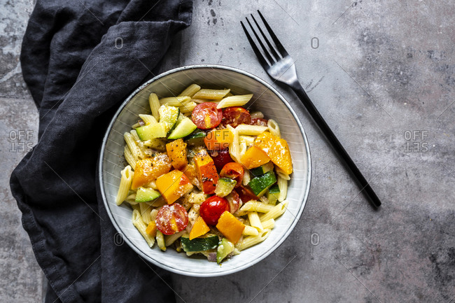 Bowl of vegan pasta with pumpkin- tomatoes and zucchini