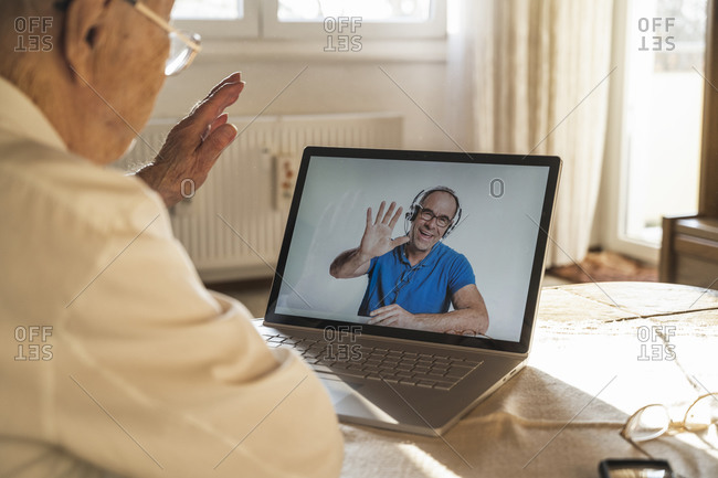 Mature man greeting senior man on video call through laptop at home