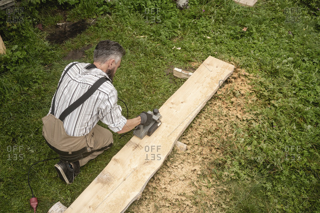 Carpenter sawing plank with circular saw