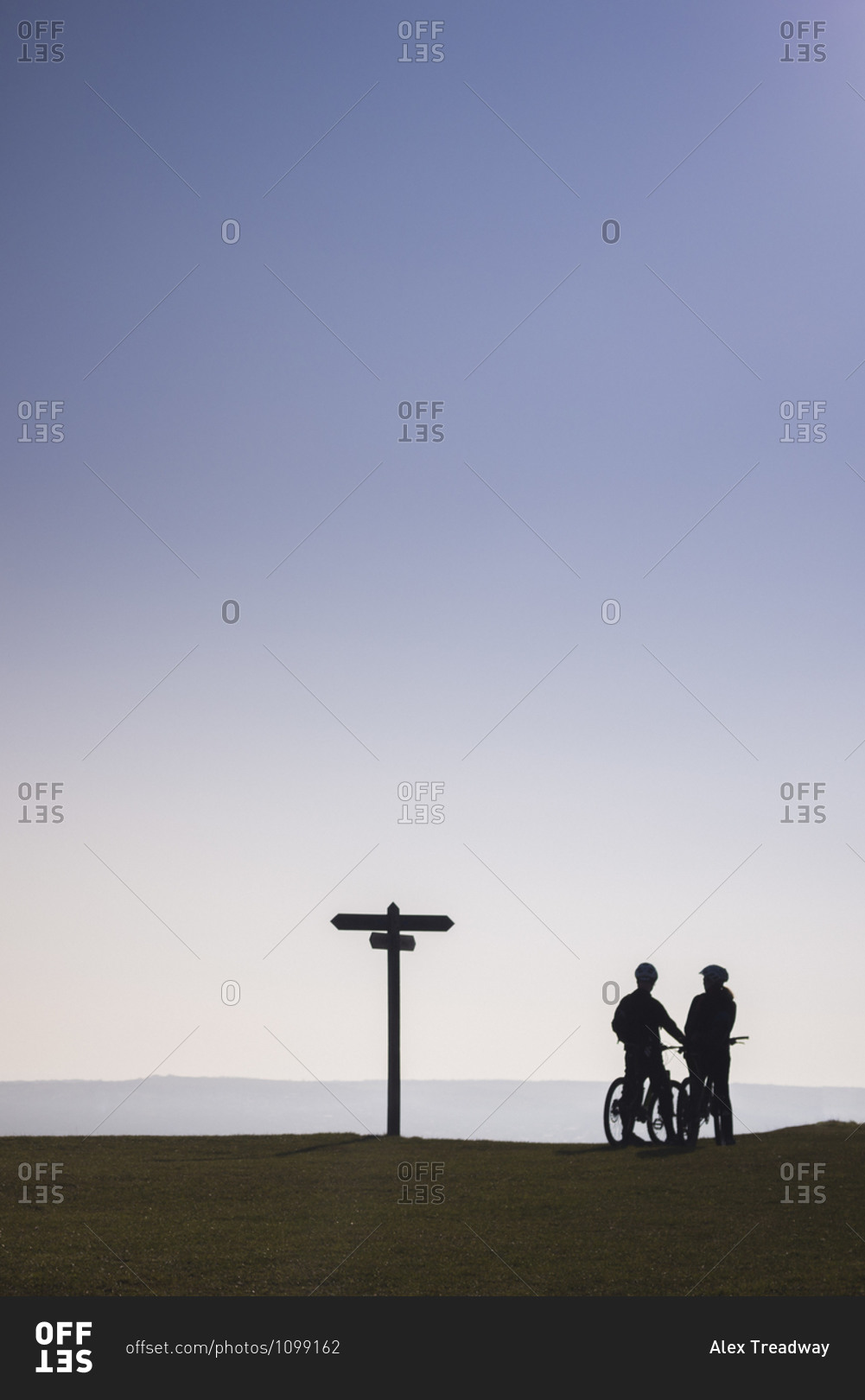Cyclists in Dorset in the UK take a break on the brow of a hill at sunset