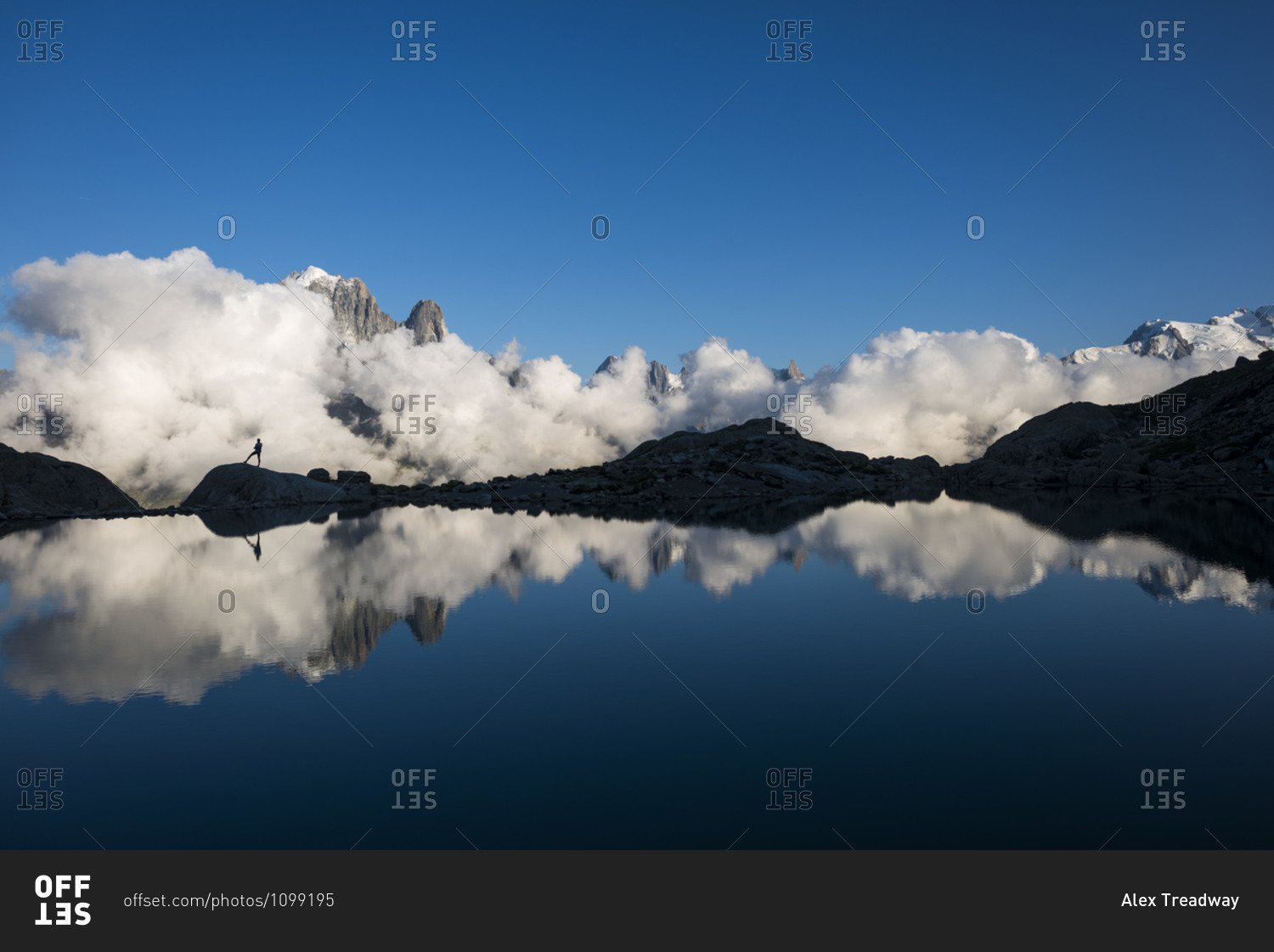 A hiker reflected in Lac Blanc on the Tour du Mont Blanc trekking route in the French Alps