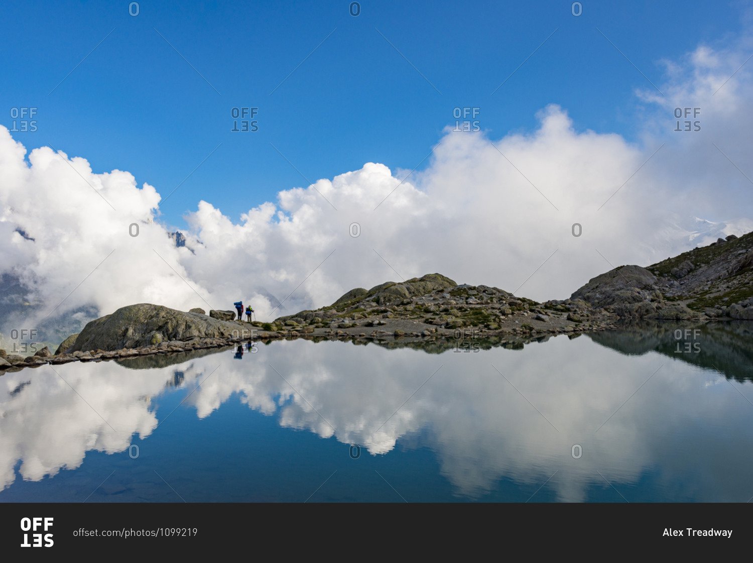 Hikers reflected in Lac Blanc on the Tour du Mont Blanc trekking route in the French Alps