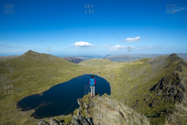 A woman stands on top of Striding Edge facing towards Red Tarn in the English Lake District
