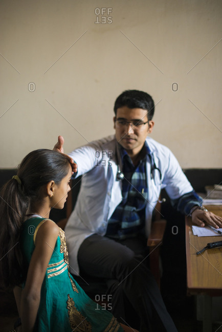 A doctor feels a little girls forehead to check her temperature with the back of his hand in Diktel hospital in Nepal