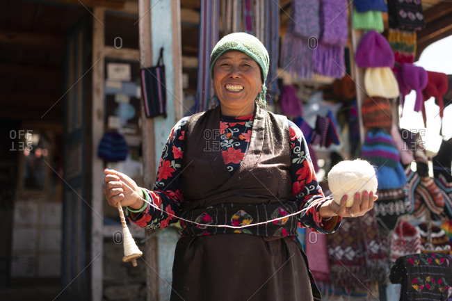 A Sherpa woman from Gosainkund spins baby Yak wool using the traditional method with a spindle