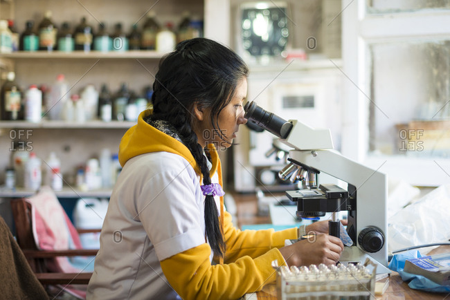 A teenage girl looks through a microscope in a laboratory in the Khotang District Hospital in Nepal