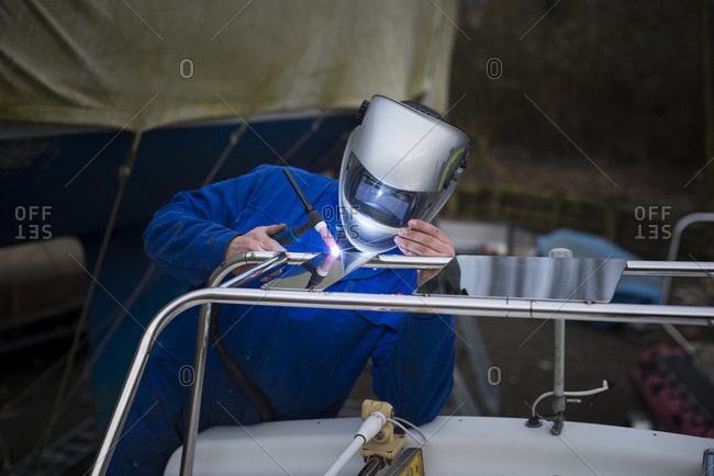 Suffolk Yacht Harbour, Levington, Ipswich, Suffolk, UK - March 5, 2015: Metal fabricator welding a steel canopy on a boat