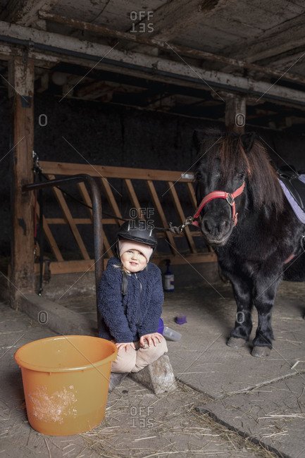Girl with pony in stable