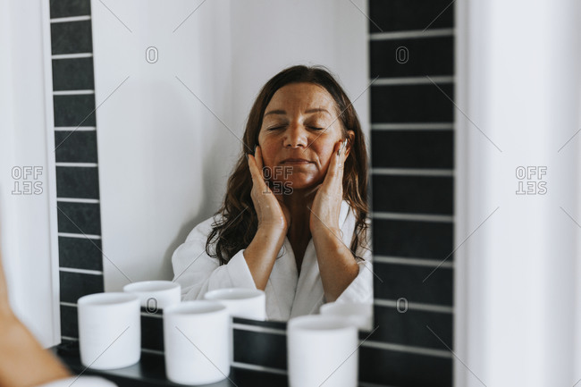 Woman applying moisturizer on her face