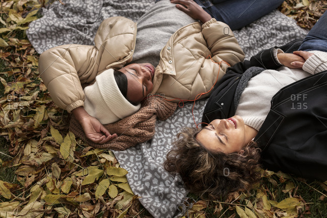 Female friends relaxing on blanket at autumn